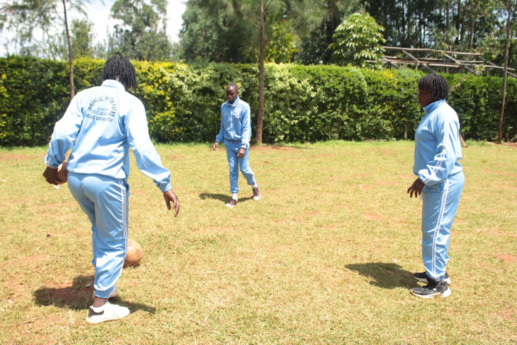 Junior secondary pupils playing football on the school field