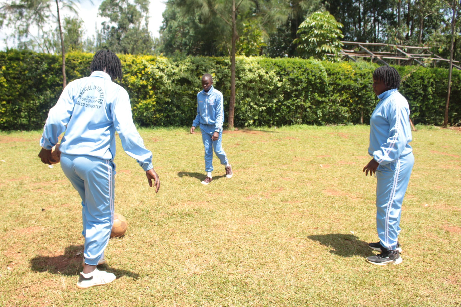 Junior secondary pupils playing football on the school field